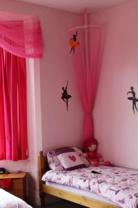 A pink bedroom with silhouettes of ballet dancers on the walls